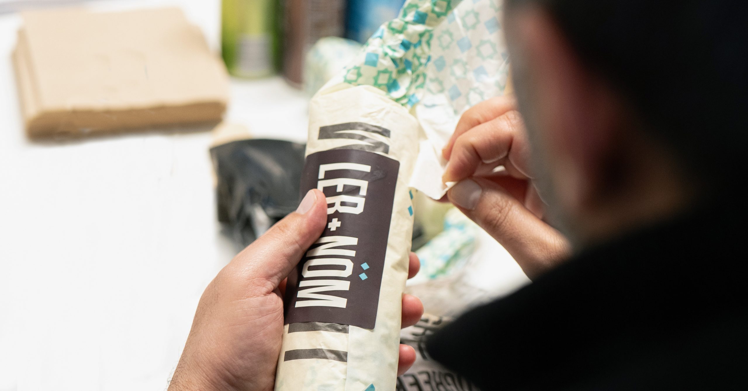 Person wrapping a branded LEB + NOM food item as part of the Dish’d plug & play kitchen system.