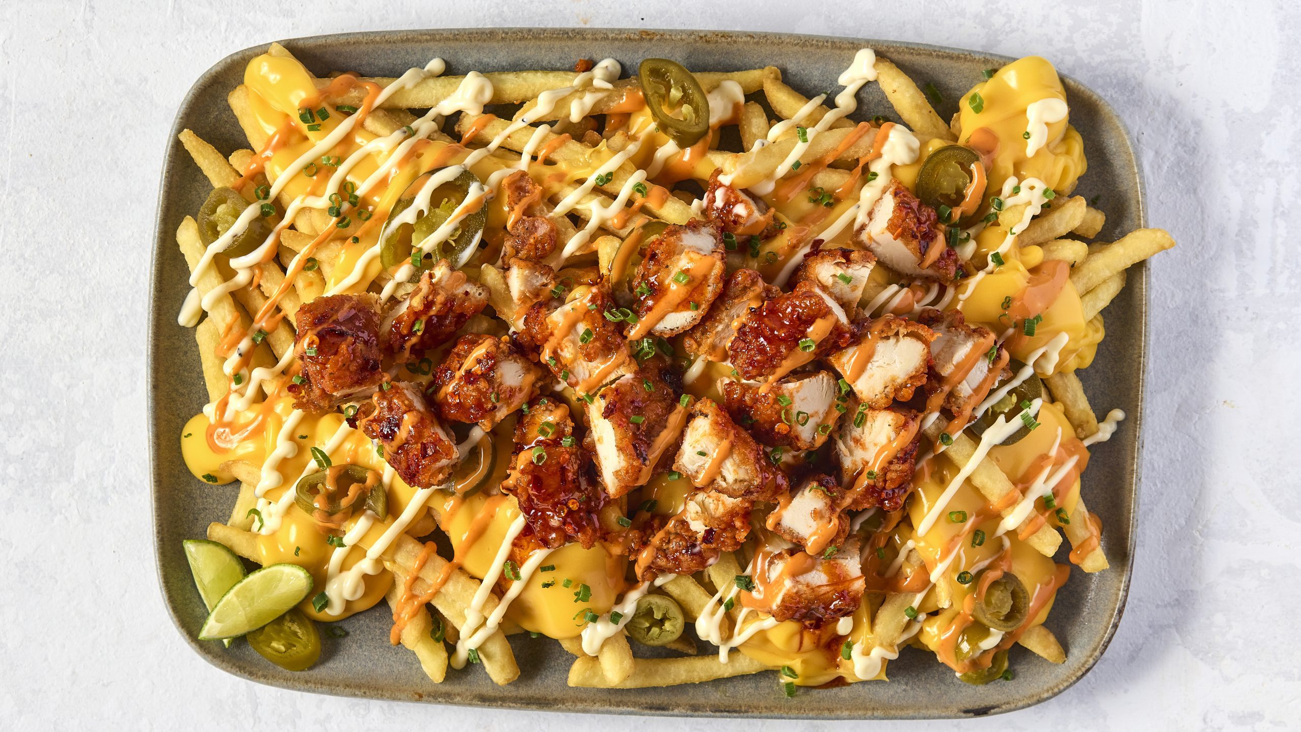 Close-up of loaded waffle fries topped with grilled chicken, jalapeños, sauces, and chives — a Dish’d virtual brand menu item.
